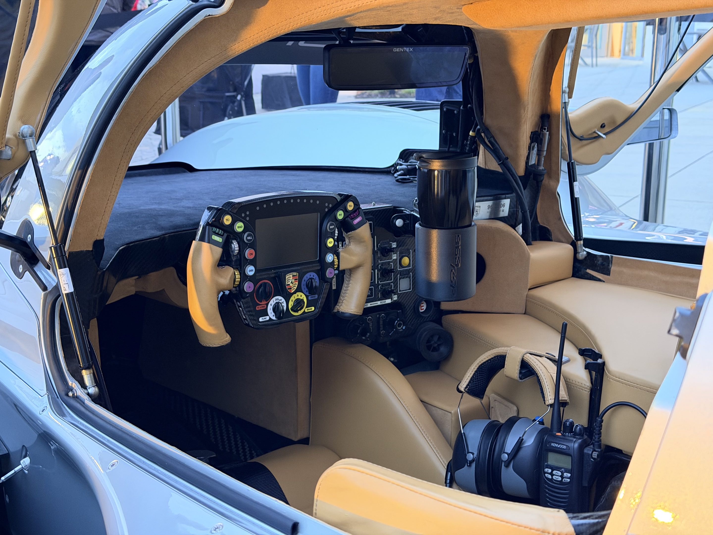The interior of the Porsche 963 RSP photographed through the left door, showing the leather materials, steering yoke, race scanner, and cup holder